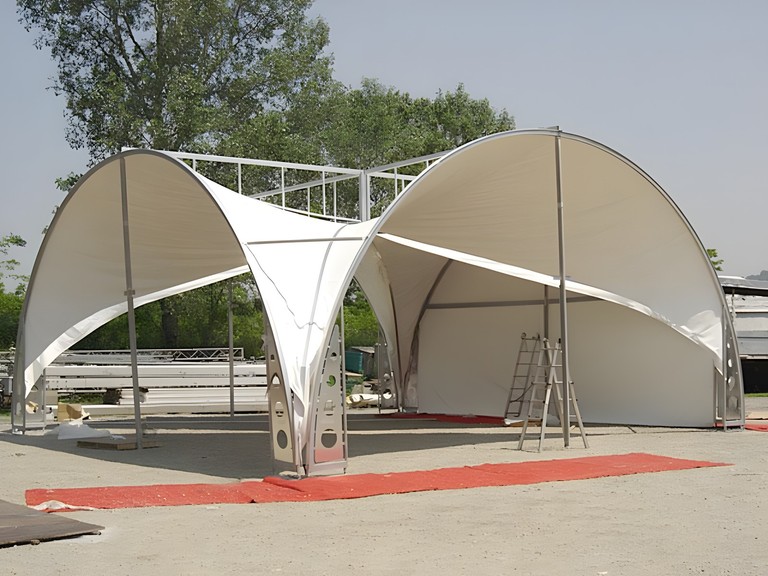 Copertura a vela su archi metallici con una passerella rossa all’ingresso